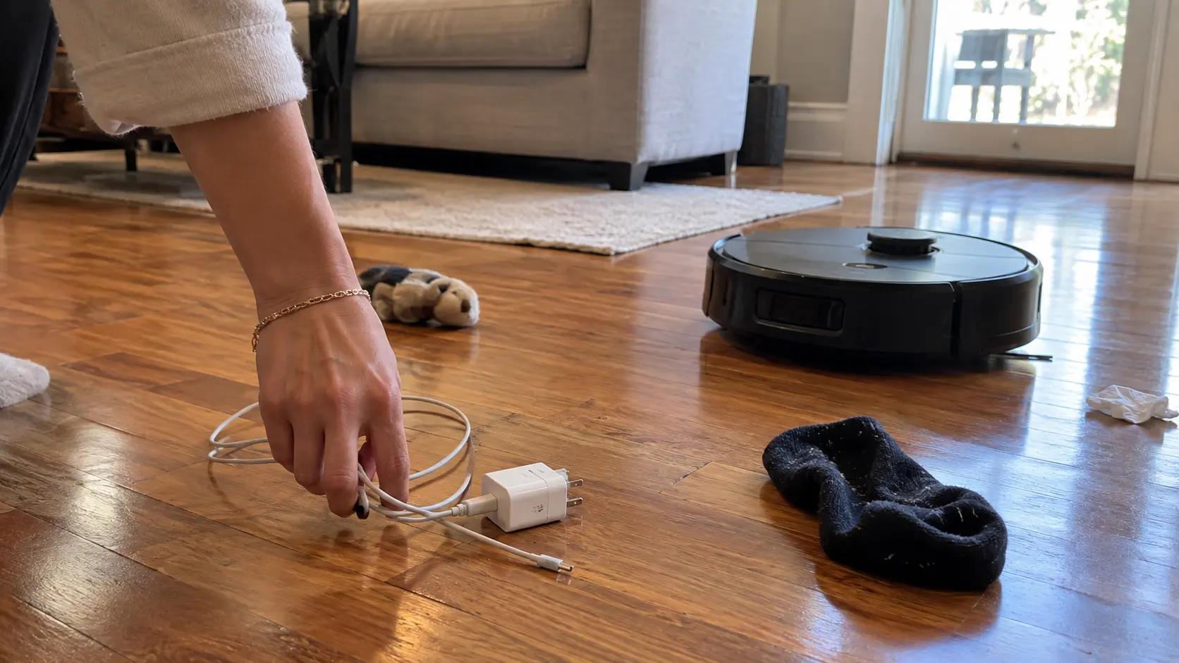 Clearing cables and socks from the floor before a robot vacuum run.