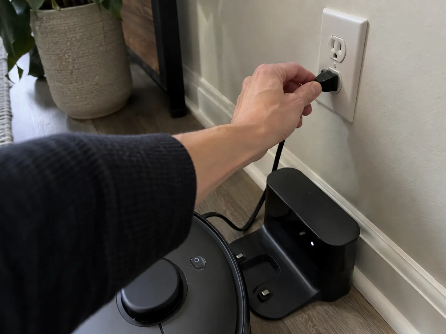 plugging in robot vacuum charging dock.